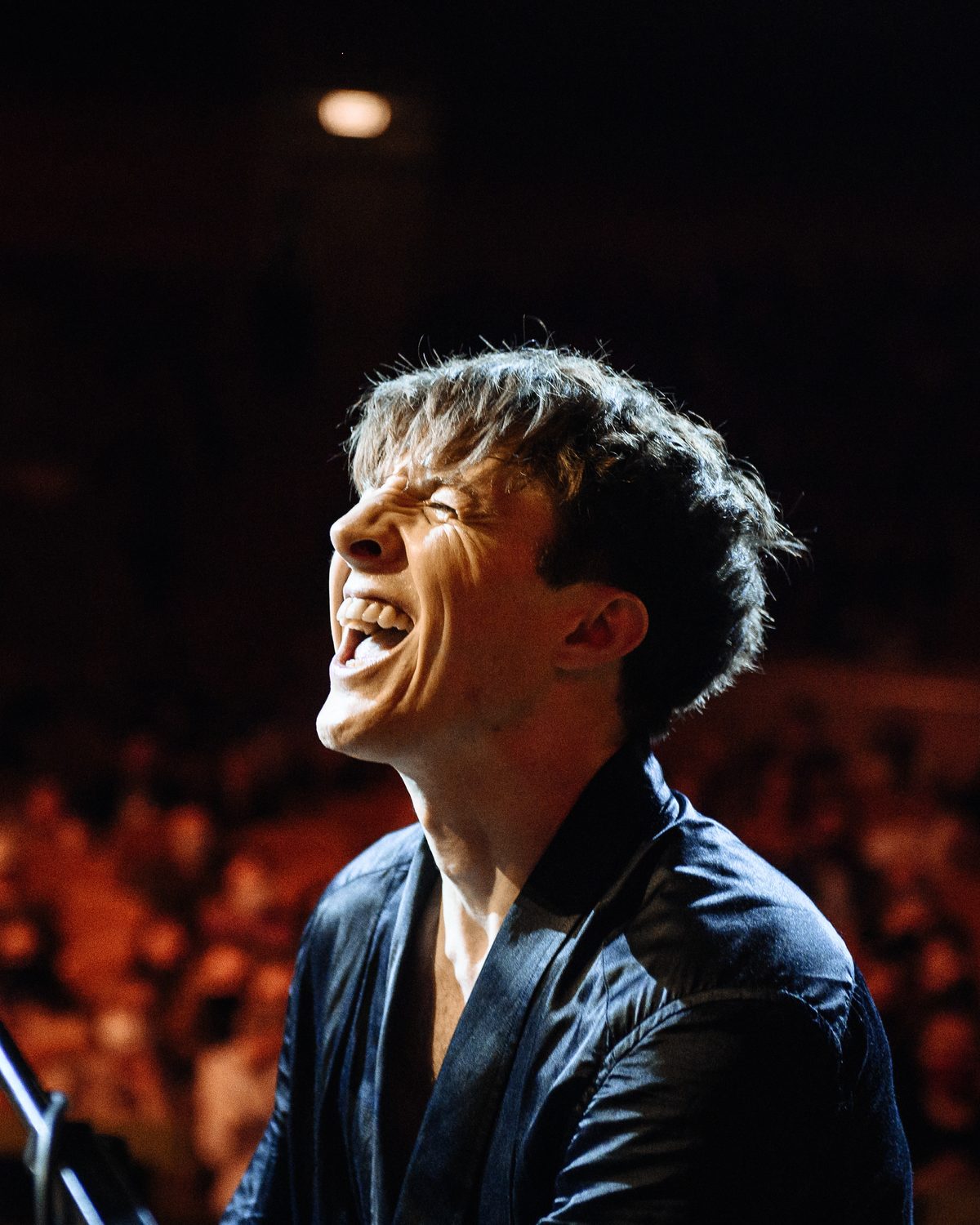Stephen Ridley singing passionately into the microphone on stage