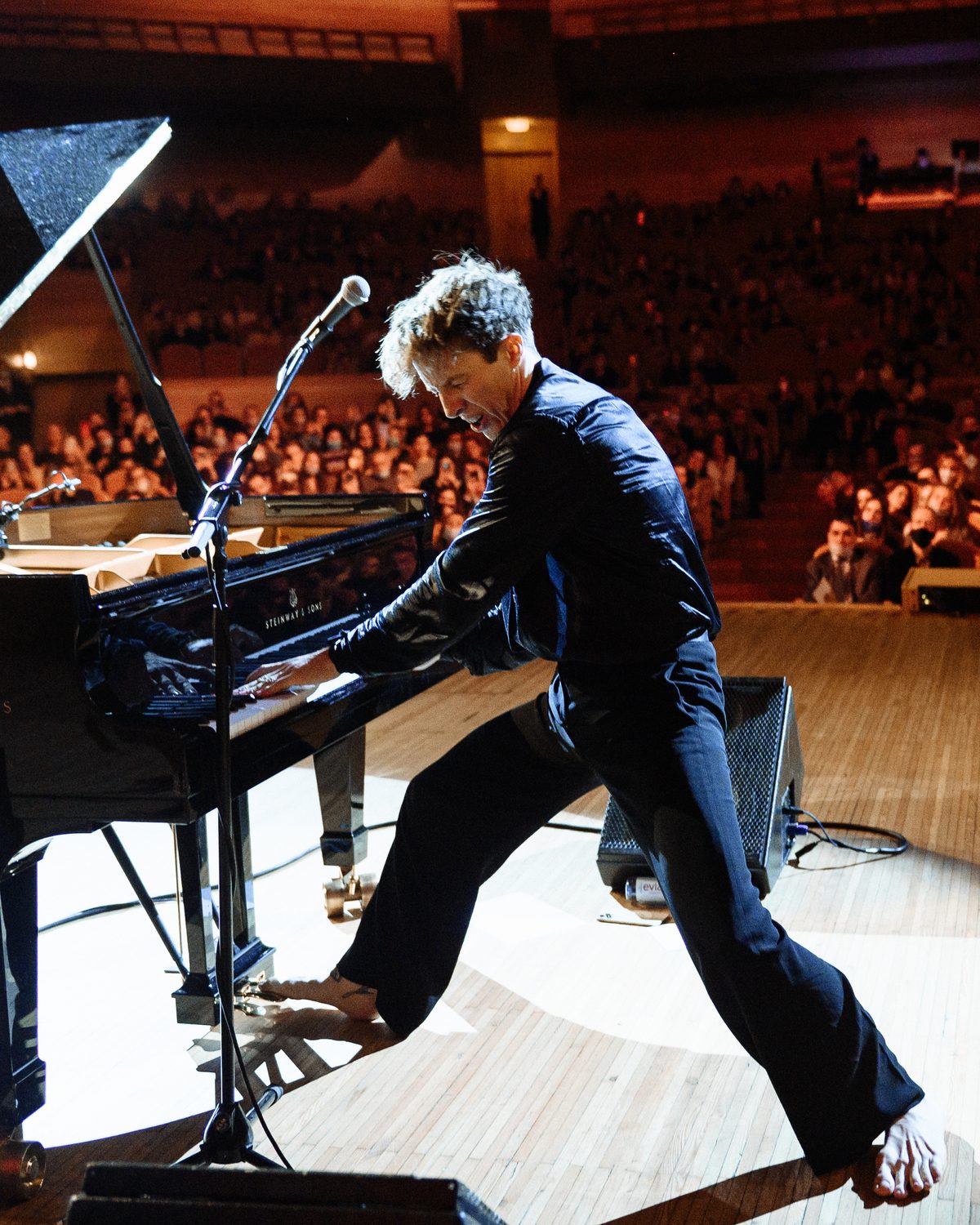 Stephen Ridley standing at the grand piano commanding a packed concert hall